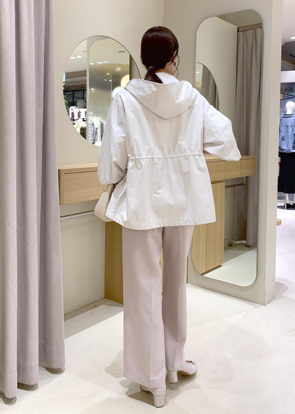 ホワイト系のショルダーバッグ、ベージュ系のパンプス、ホワイト系のナイロンジャケットを着用したレディースの春コーディネートの4枚目の写真