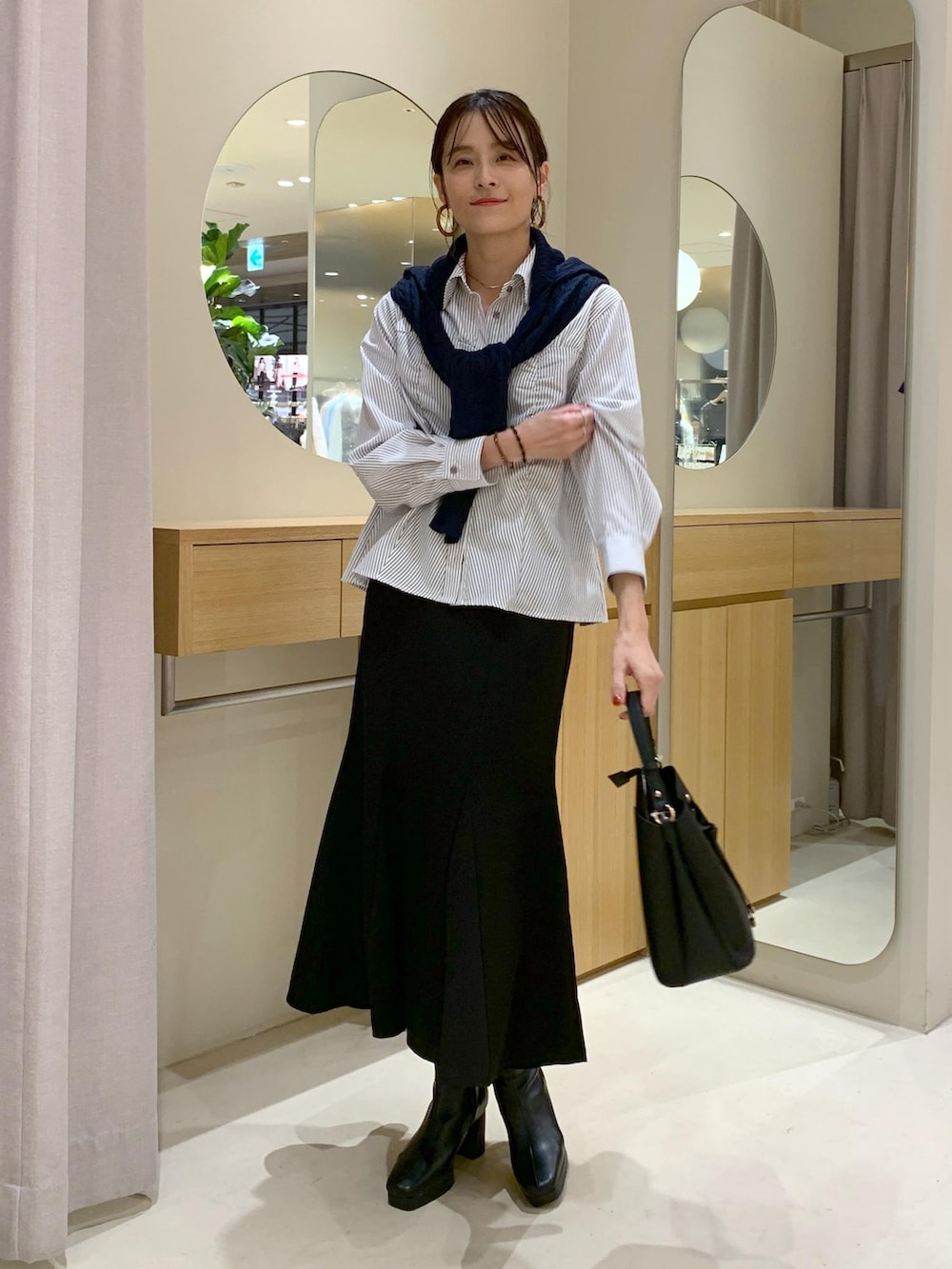 ブラック系のショルダーバッグ、ブラック系のスカート、ブルー系のカーディガン/ボレロを着用したレディースの秋コーディネートの5枚目の写真
