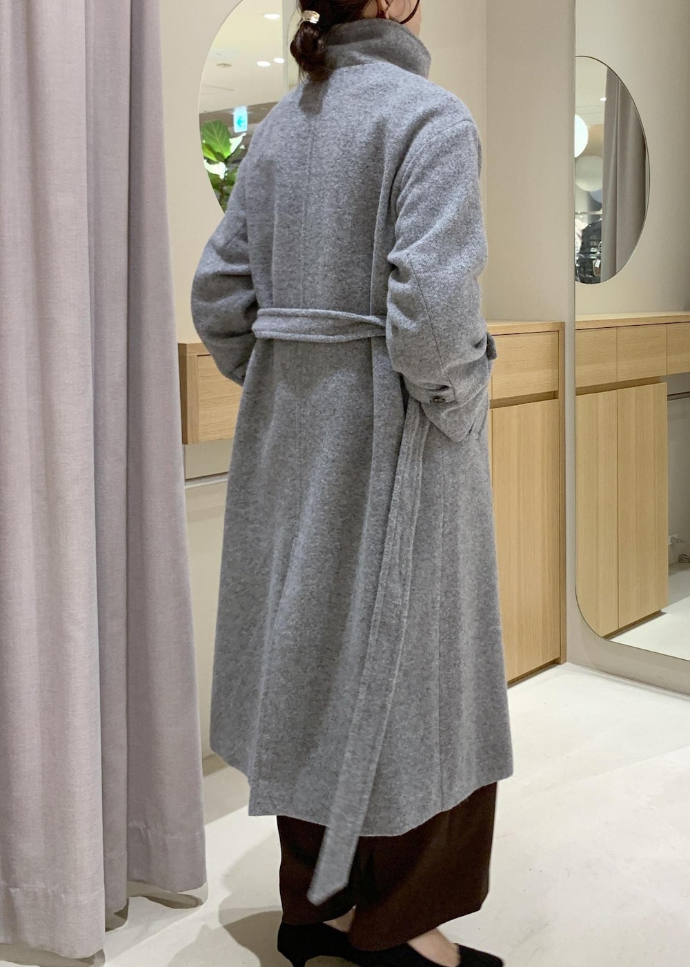 ブルー系のハンドバッグ、ブラウン系のスラックス、グレー系のその他アウターを着用したレディースの冬コーディネートの4枚目の写真