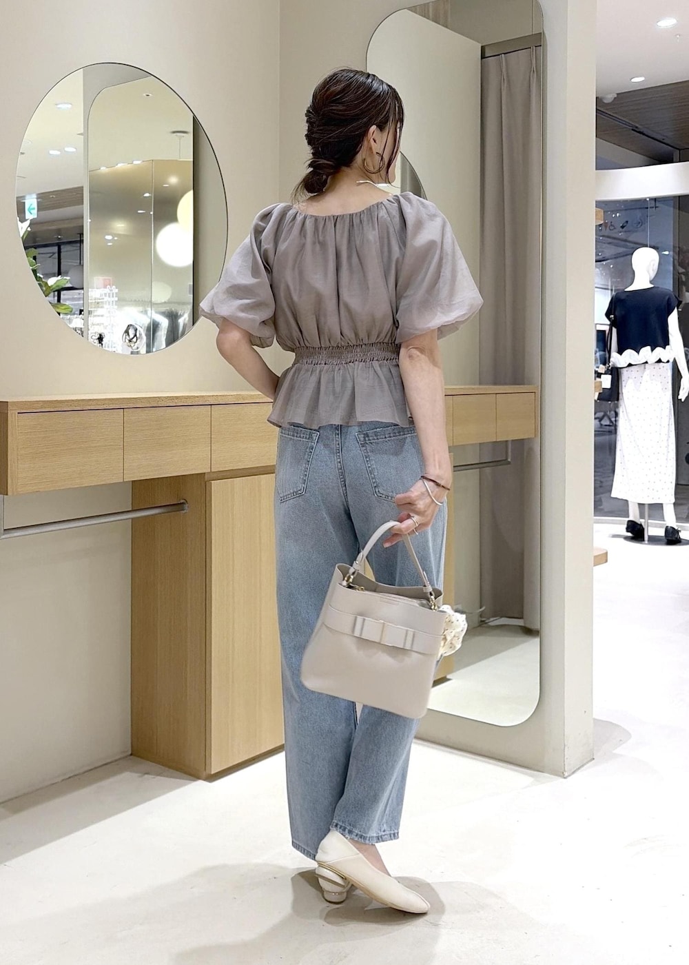 ホワイト系のパンプス、ベージュ系のシャツ/ブラウス、ブルー系のデニムパンツを着用したレディースの夏コーディネートの4枚目の写真