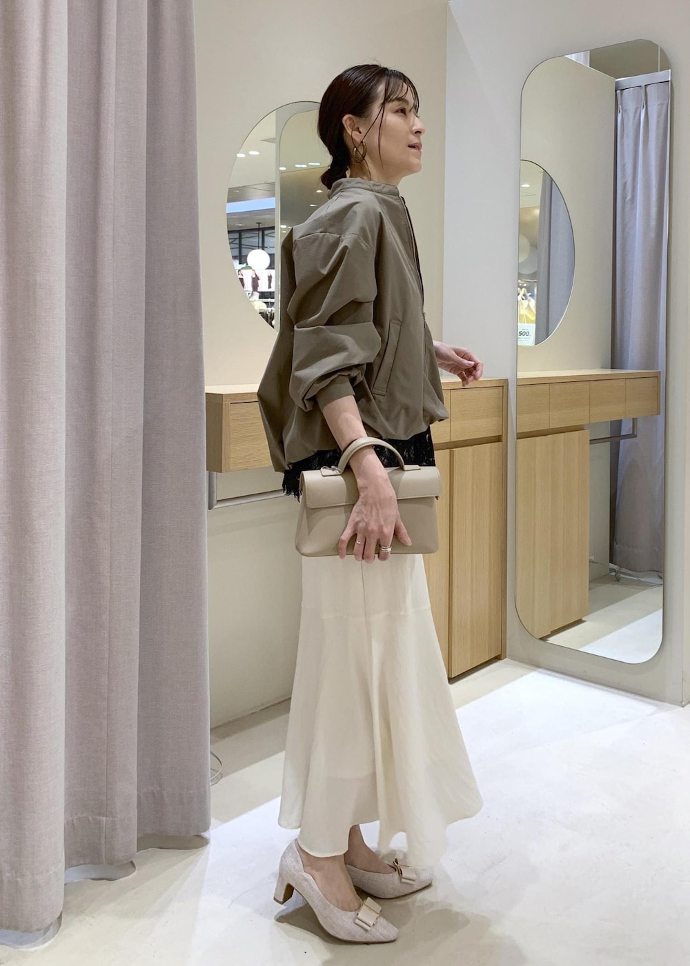 ベージュ系のパンプス、ホワイト系のスカート、ブラック系のキャミソールを着用したレディースの春コーディネートの3枚目の写真