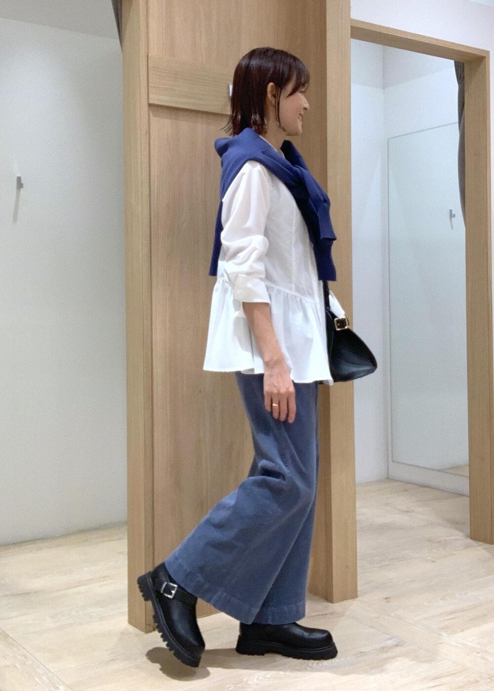 ブラック系のブーツ、ブラック系のトートバッグ、ブルー系のカーディガン/ボレロを着用したレディースの秋コーディネートの2枚目の写真