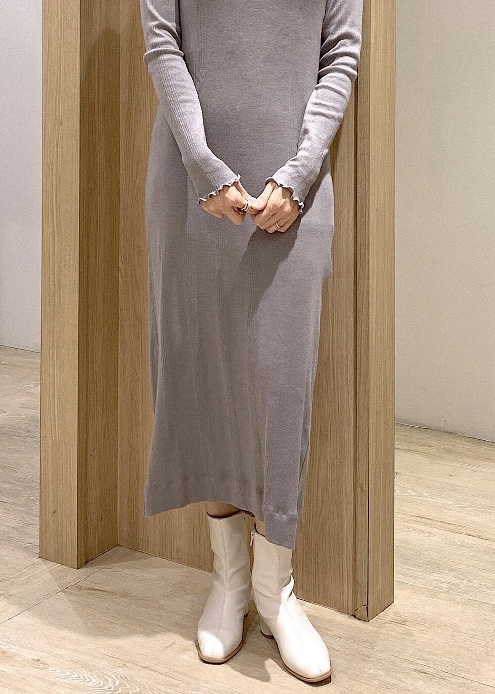 シルバー系のショルダーバッグ、ホワイト系のブーツ、グレー系のワンピースを着用したレディースの冬コーディネートの7枚目の写真