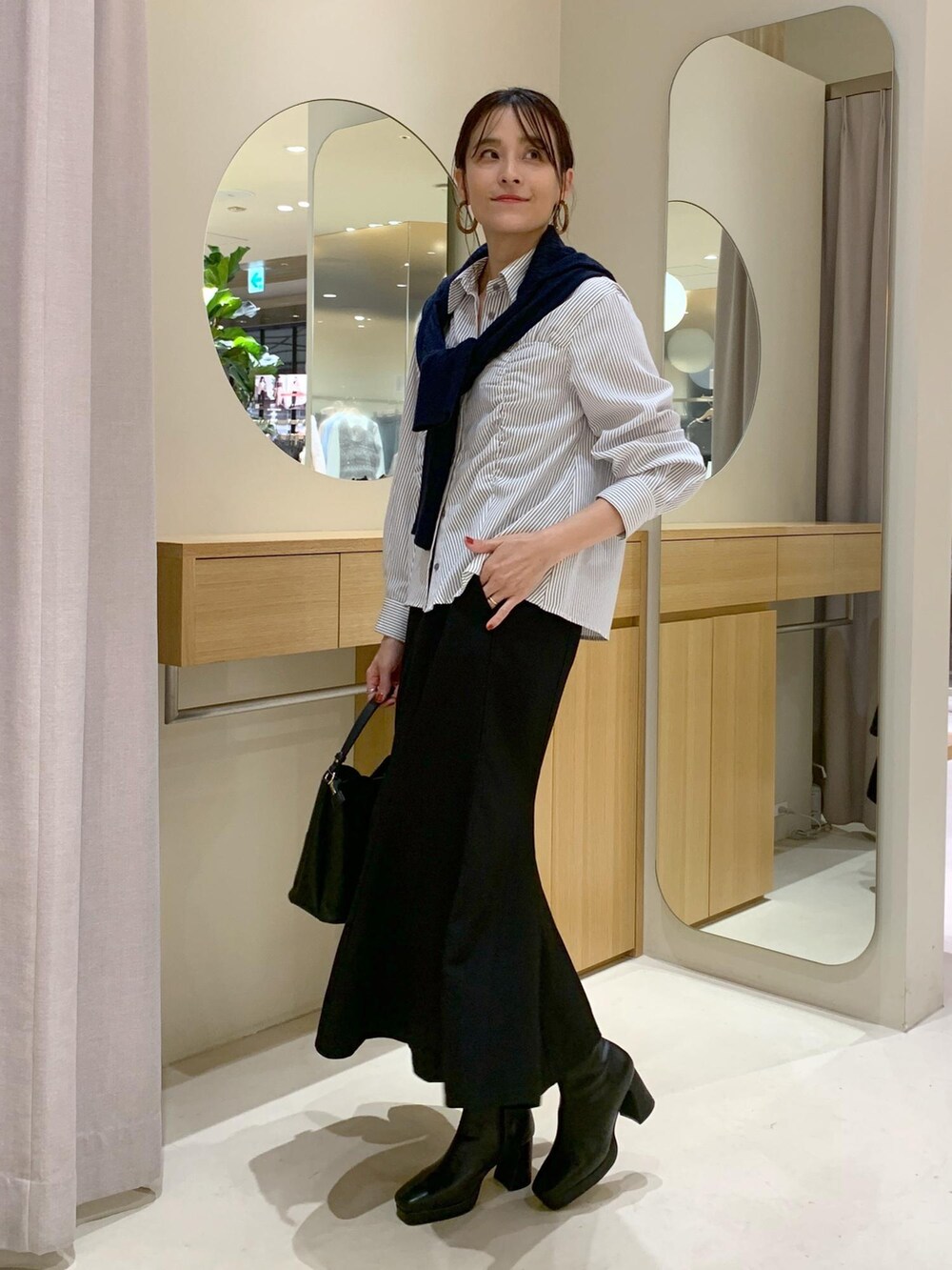 ブラック系のショルダーバッグ、ブラック系のスカート、ブルー系のカーディガン/ボレロを着用したレディースの秋コーディネートの6枚目の写真