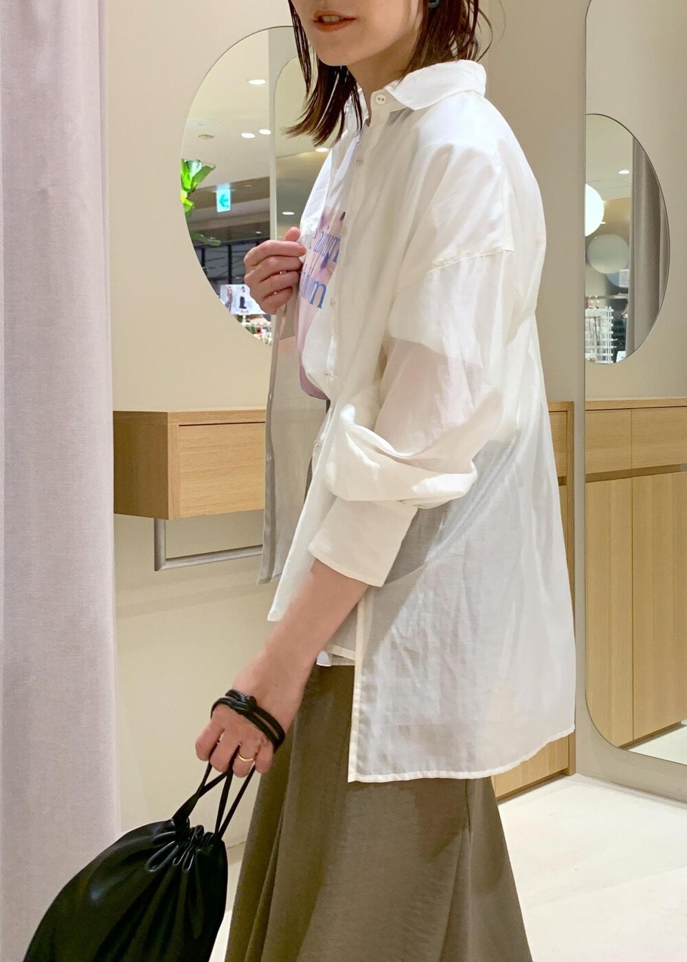 グリーン系のスカート、ホワイト系のシャツ/ブラウス、ブラック系のハンドバッグを着用したレディースの春コーディネートの9枚目の写真