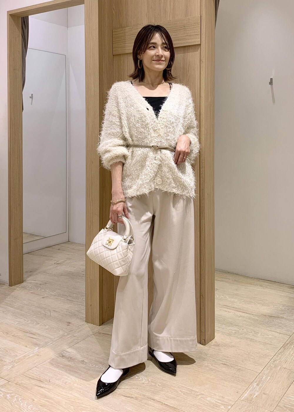 ブラック系のキャミソール、ホワイト系のカーディガン/ボレロ、ベージュ系のその他パンツを着用したレディースの冬コーディネートの2枚目の写真