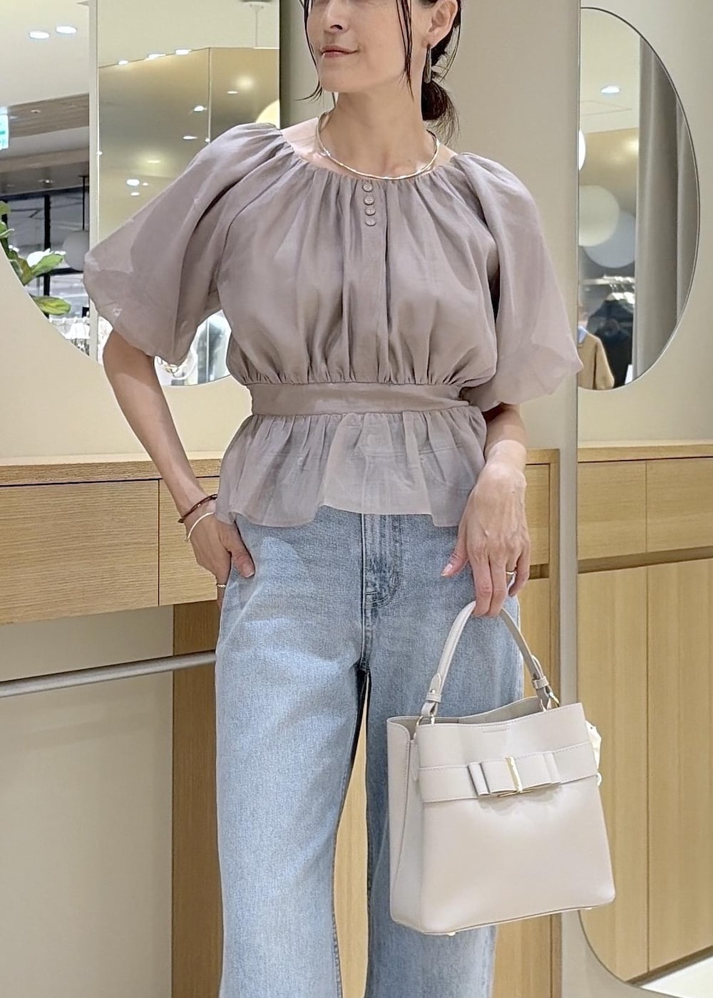 ホワイト系のパンプス、ベージュ系のシャツ/ブラウス、ブルー系のデニムパンツを着用したレディースの夏コーディネートの6枚目の写真