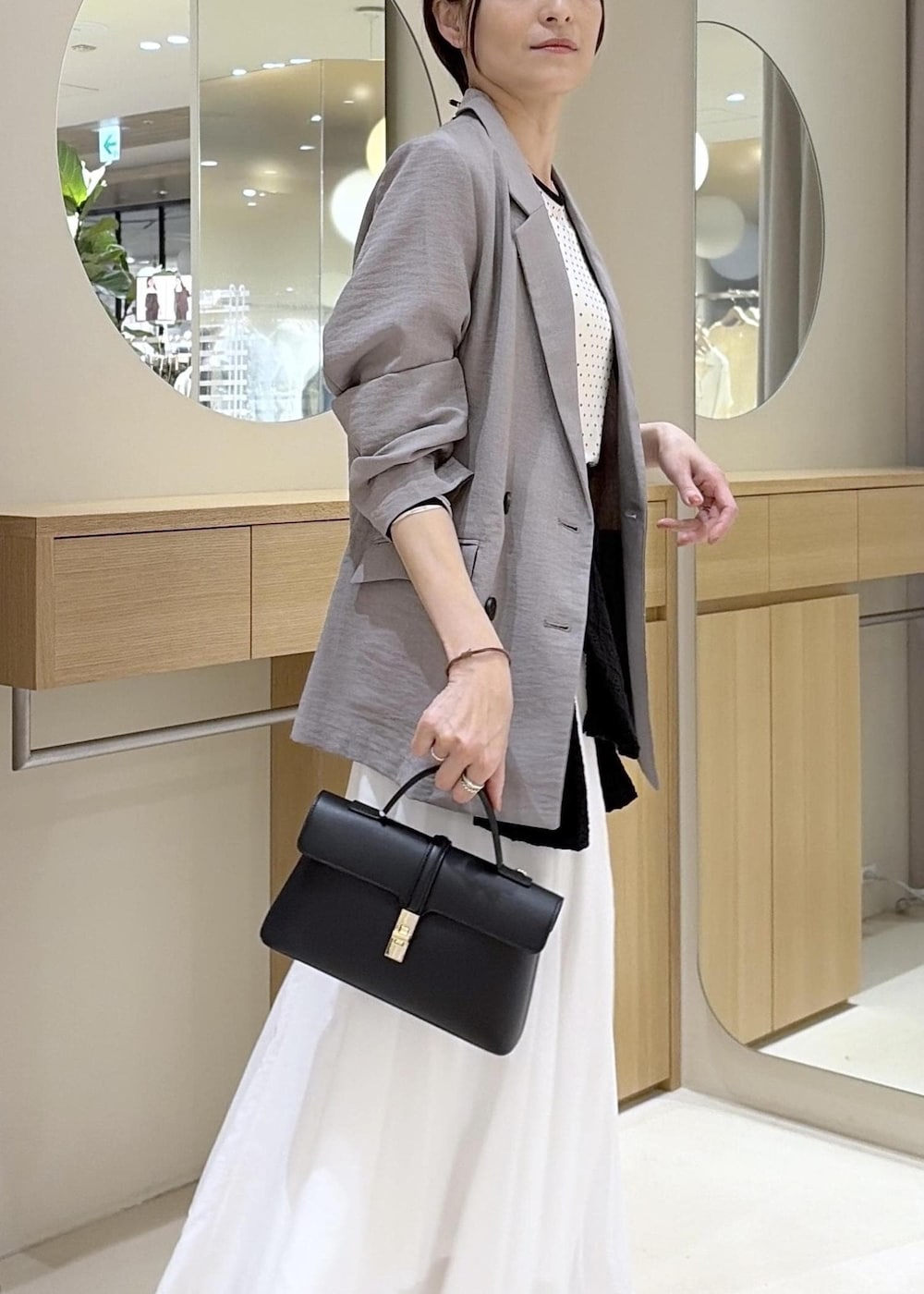 ブラウン系のパンプス、ホワイト系のスカート、ブラック系のカーディガン/ボレロを着用したレディースの春コーディネートの6枚目の写真