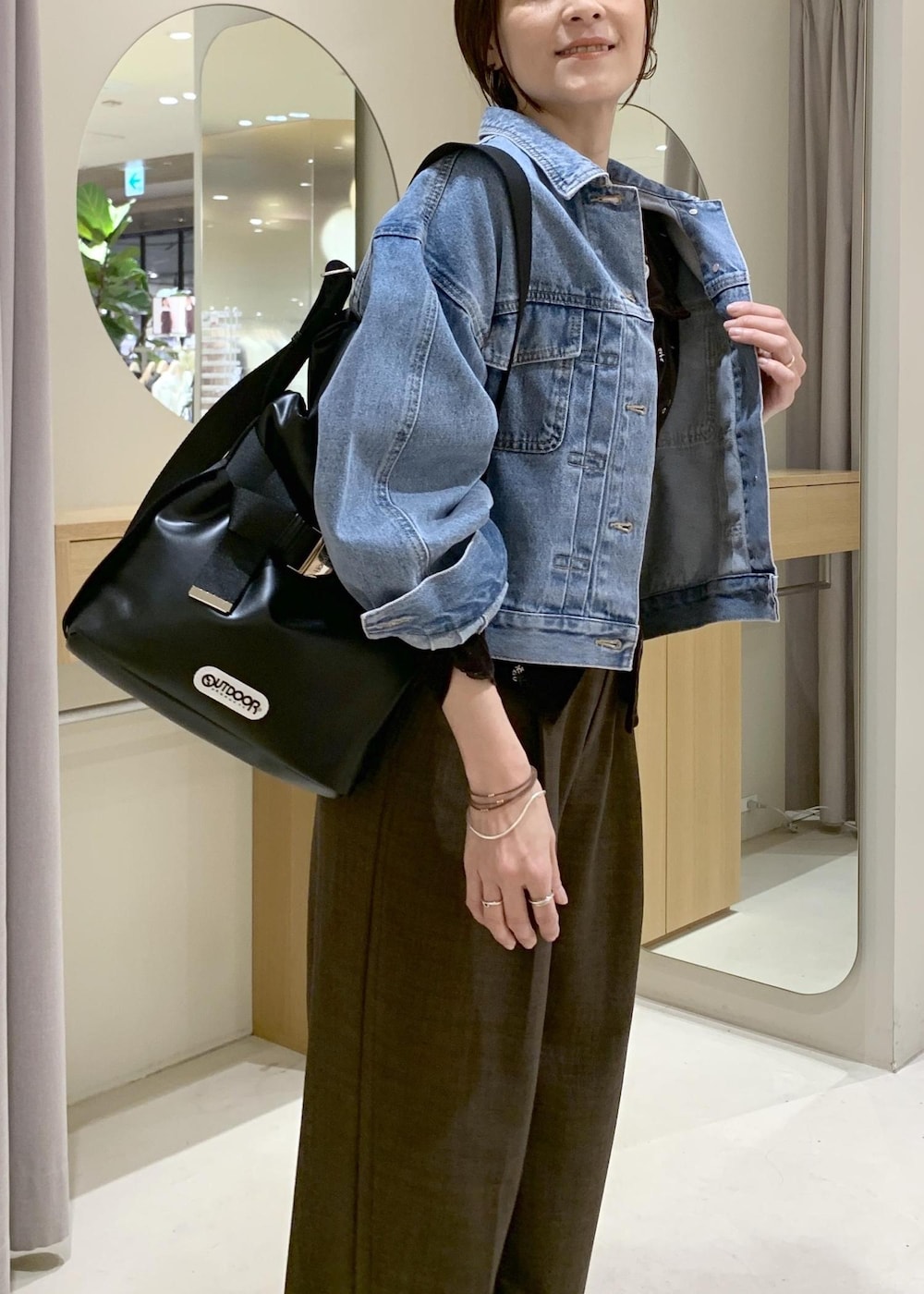 ブルー系のデニムジャケット、ブラック系のトートバッグ、ブラウン系のカーディガン/ボレロを着用したレディースの春コーディネートの5枚目の写真