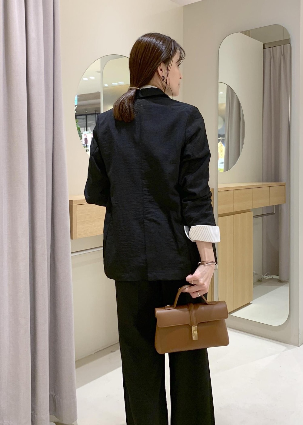 イエロー系のショルダーバッグ、ブラック系のテーラードジャケット、ブラック系のその他パンツを着用したレディースの春コーディネートの3枚目の写真