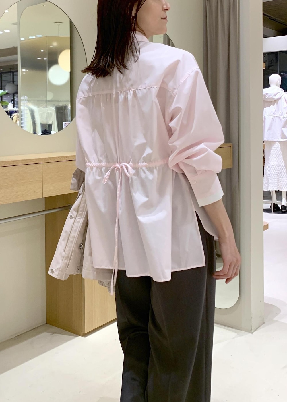 ベージュ系のハンドバッグ、ピンク系のナイロンジャケット、グレー系のスラックスを着用したレディースの春コーディネートの10枚目の写真