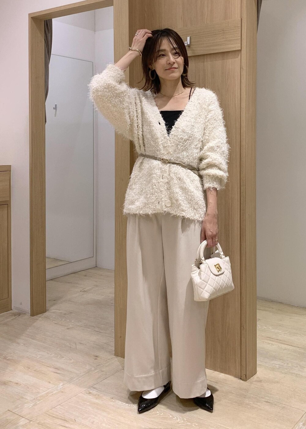 ブラック系のキャミソール、ホワイト系のカーディガン/ボレロ、ベージュ系のその他パンツを着用したレディースの冬コーディネートの3枚目の写真