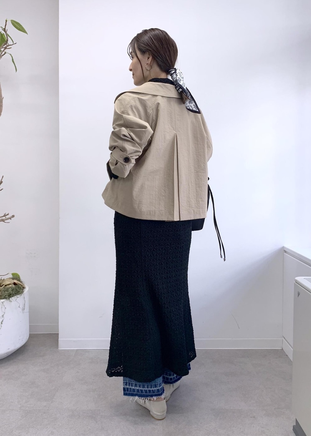 ブラック系のショルダーバッグ、ベージュ系のトレンチコート、ブルー系のデニムパンツを着用したレディースの冬コーディネートの3枚目の写真