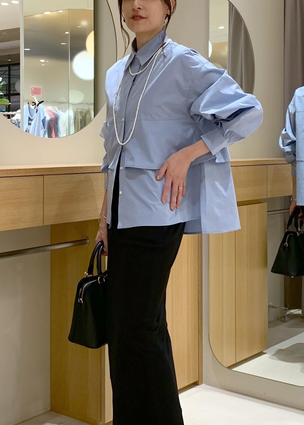 ブラック系のパンプス、ブラック系のスカート、ブルー系のシャツ/ブラウスを着用したレディースの夏コーディネートの5枚目の写真