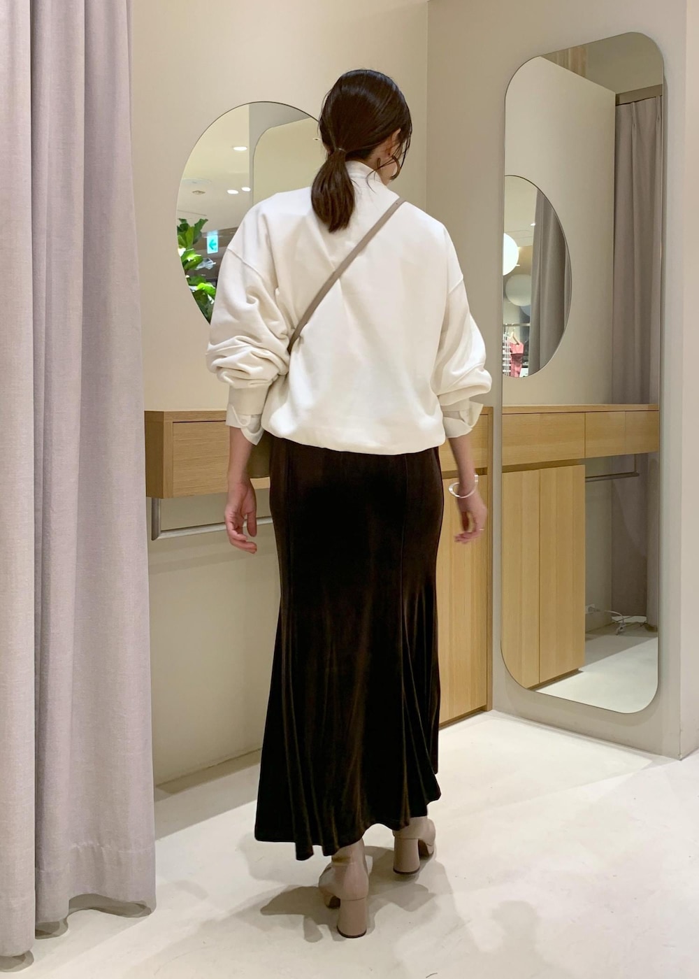 ベージュ系のショルダーバッグ、ブラウン系のスカート、ベージュ系のブーツを着用したレディースの秋コーディネートの3枚目の写真