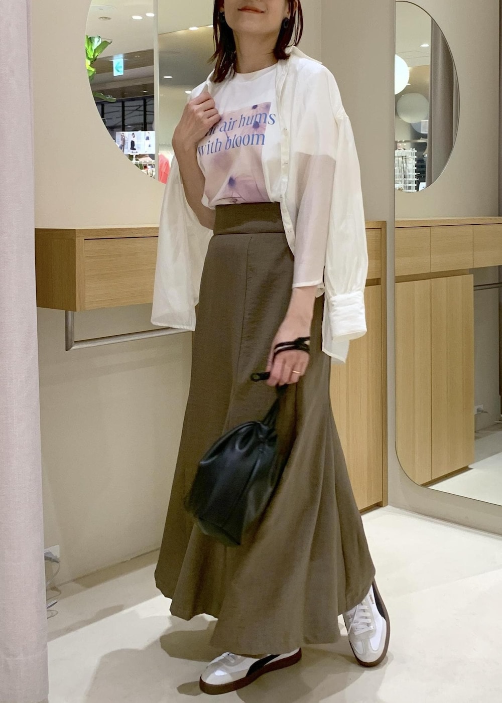 グリーン系のスカート、ホワイト系のシャツ/ブラウス、ブラック系のハンドバッグを着用したレディースの春コーディネートの3枚目の写真