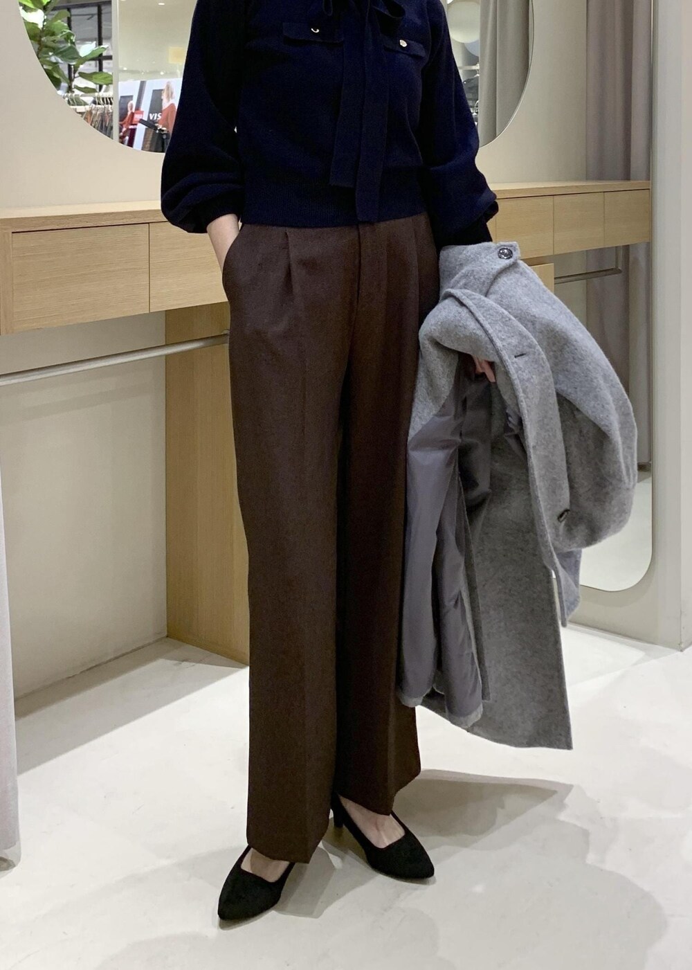 ブルー系のハンドバッグ、ブラウン系のスラックス、グレー系のその他アウターを着用したレディースの冬コーディネートの7枚目の写真