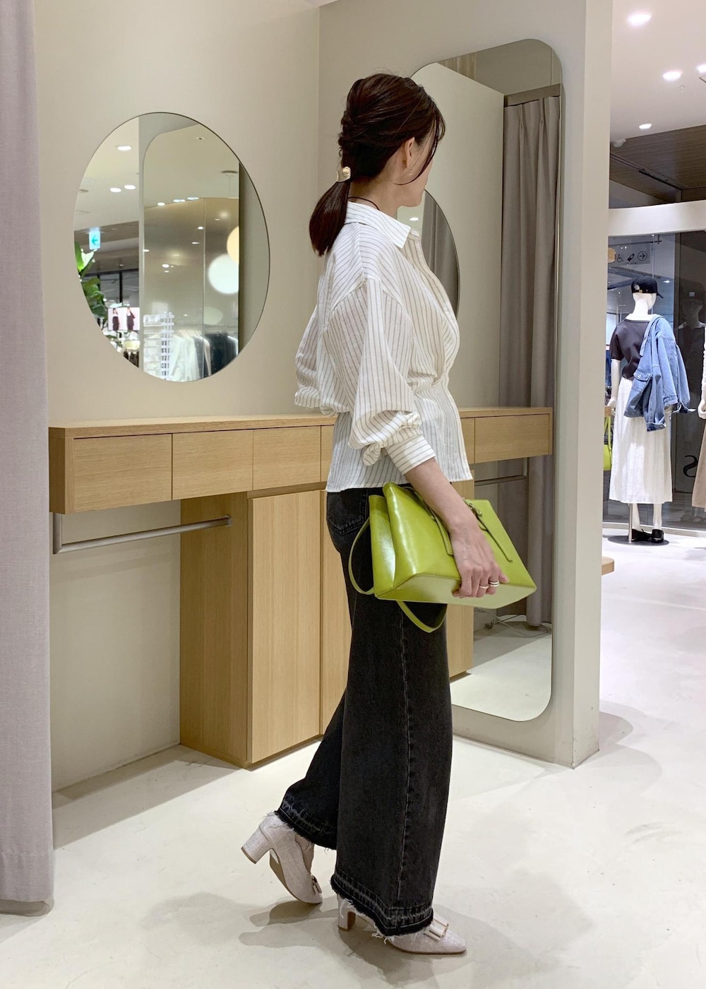 ホワイト系のキャミソール、ベージュ系のパンプス、ブラック系のデニムパンツを着用したレディースの春コーディネートの2枚目の写真