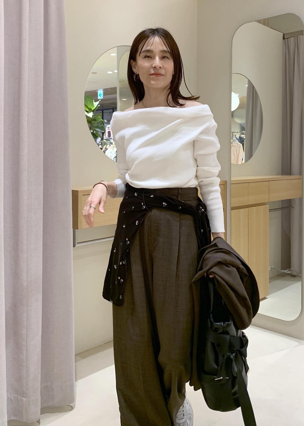 ブラック系のトートバッグ、ブラウン系のカーディガン/ボレロ、ホワイト系のニット/セーターを着用したレディースの春コーディネートの7枚目の写真