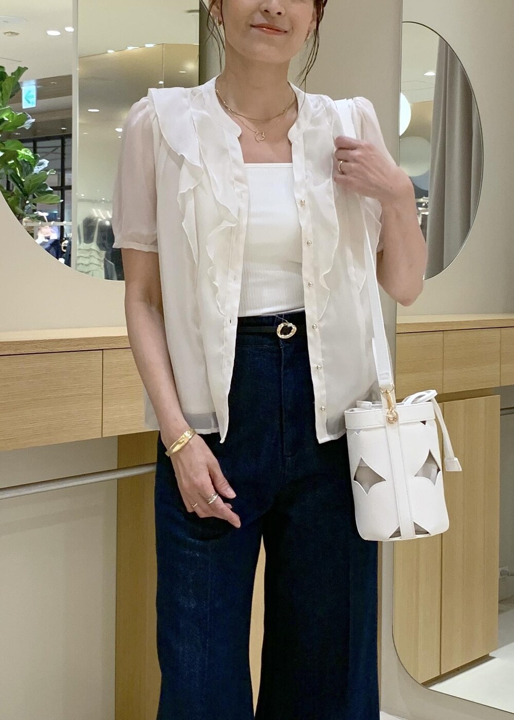 ホワイト系のキャミソール、ブラック系のサンダル、ブルー系のデニムパンツを着用したレディースの夏コーディネートの5枚目の写真