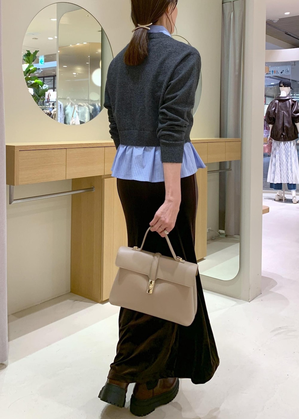 ベージュ系のハンドバッグ、ブラウン系のブーツ、ブラウン系のスカートを着用したレディースの秋コーディネートの3枚目の写真