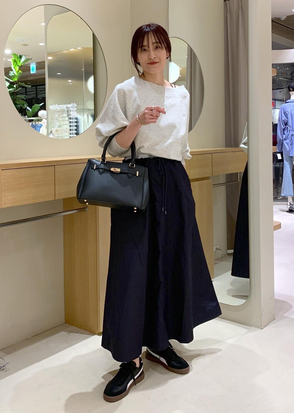 ブラック系のキャミソール、ブルー系のスカート、ホワイト系のスウェットを着用したレディースの春コーディネートの2枚目の写真