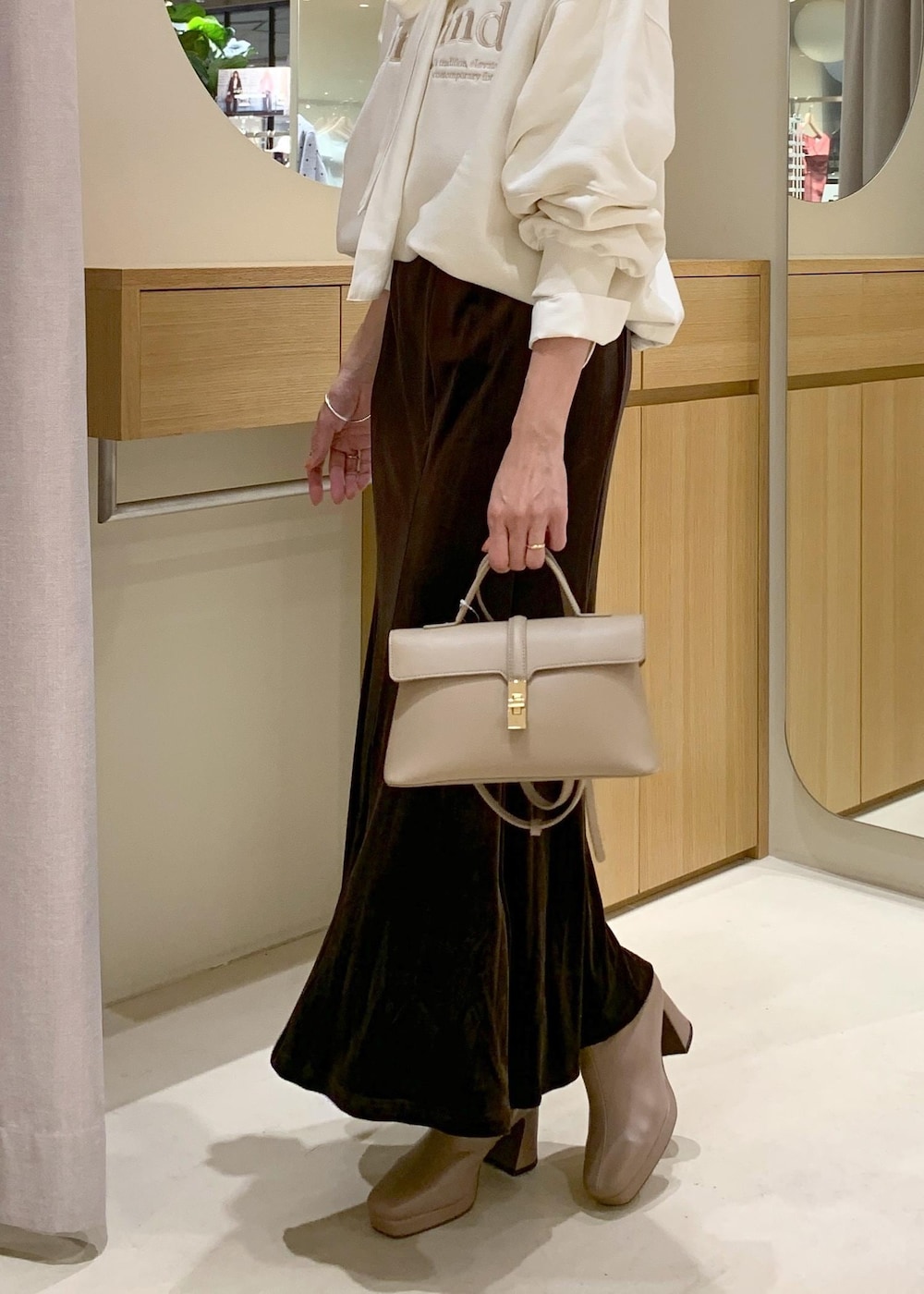 ベージュ系のショルダーバッグ、ブラウン系のスカート、ベージュ系のブーツを着用したレディースの秋コーディネートの7枚目の写真