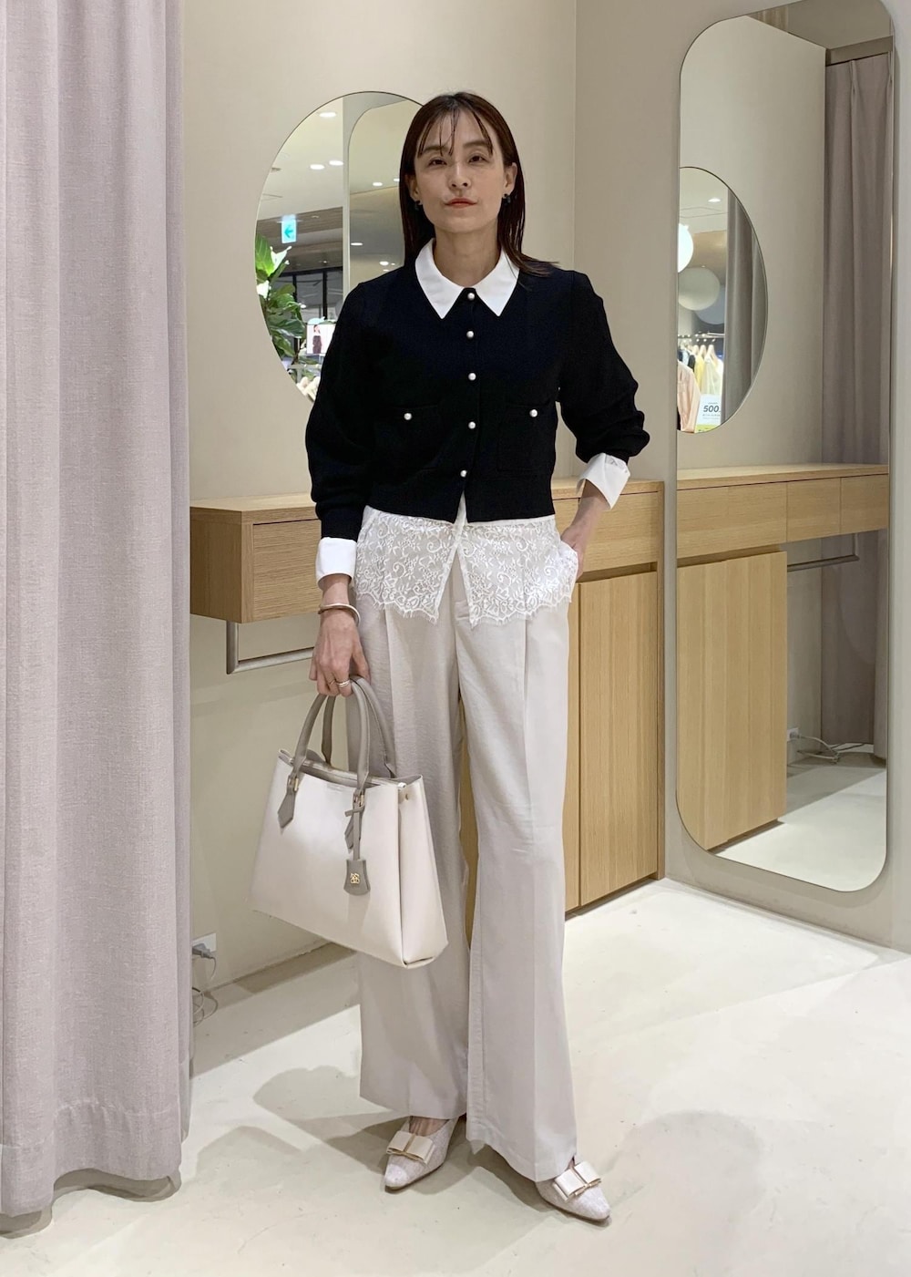 ベージュ系のパンプス、ホワイト系のシャツ/ブラウス、ブラック系のカーディガン/ボレロを着用したレディースの春コーディネートの2枚目の写真