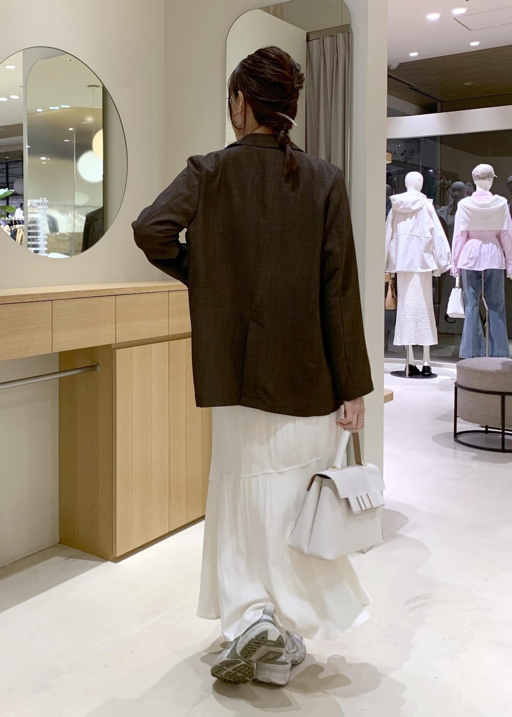 ホワイト系のハンドバッグ、ホワイト系のスカート、ホワイト系のニット/セーターを着用したレディースの春コーディネートの4枚目の写真