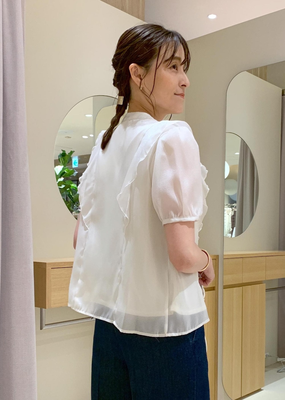 ホワイト系のキャミソール、ブラック系のサンダル、ブルー系のデニムパンツを着用したレディースの夏コーディネートの7枚目の写真