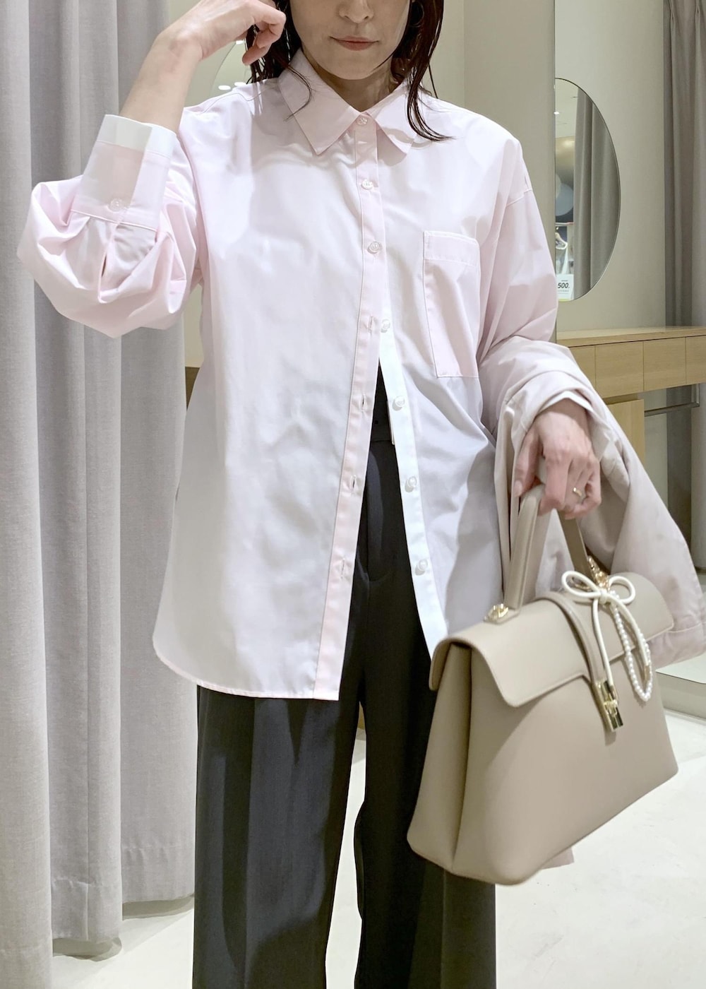 ベージュ系のハンドバッグ、ピンク系のナイロンジャケット、グレー系のスラックスを着用したレディースの春コーディネートの9枚目の写真