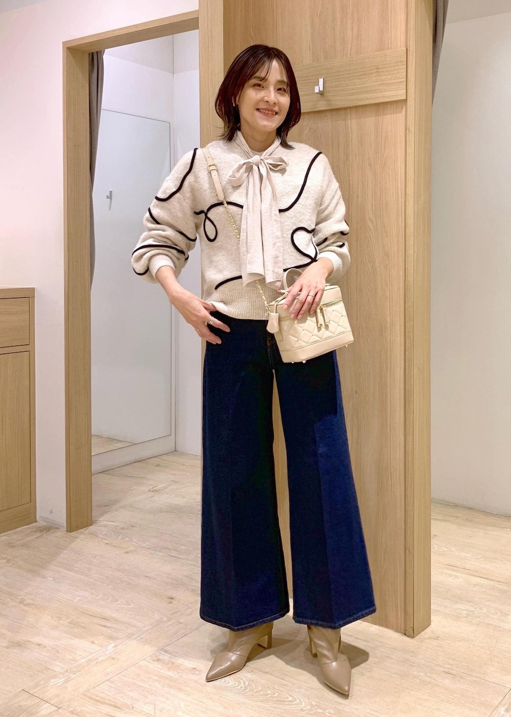 ブルー系のデニムパンツ、ベージュ系のブーツ、ホワイト系のシャツ/ブラウスを着用したレディースの冬コーディネートの2枚目の写真