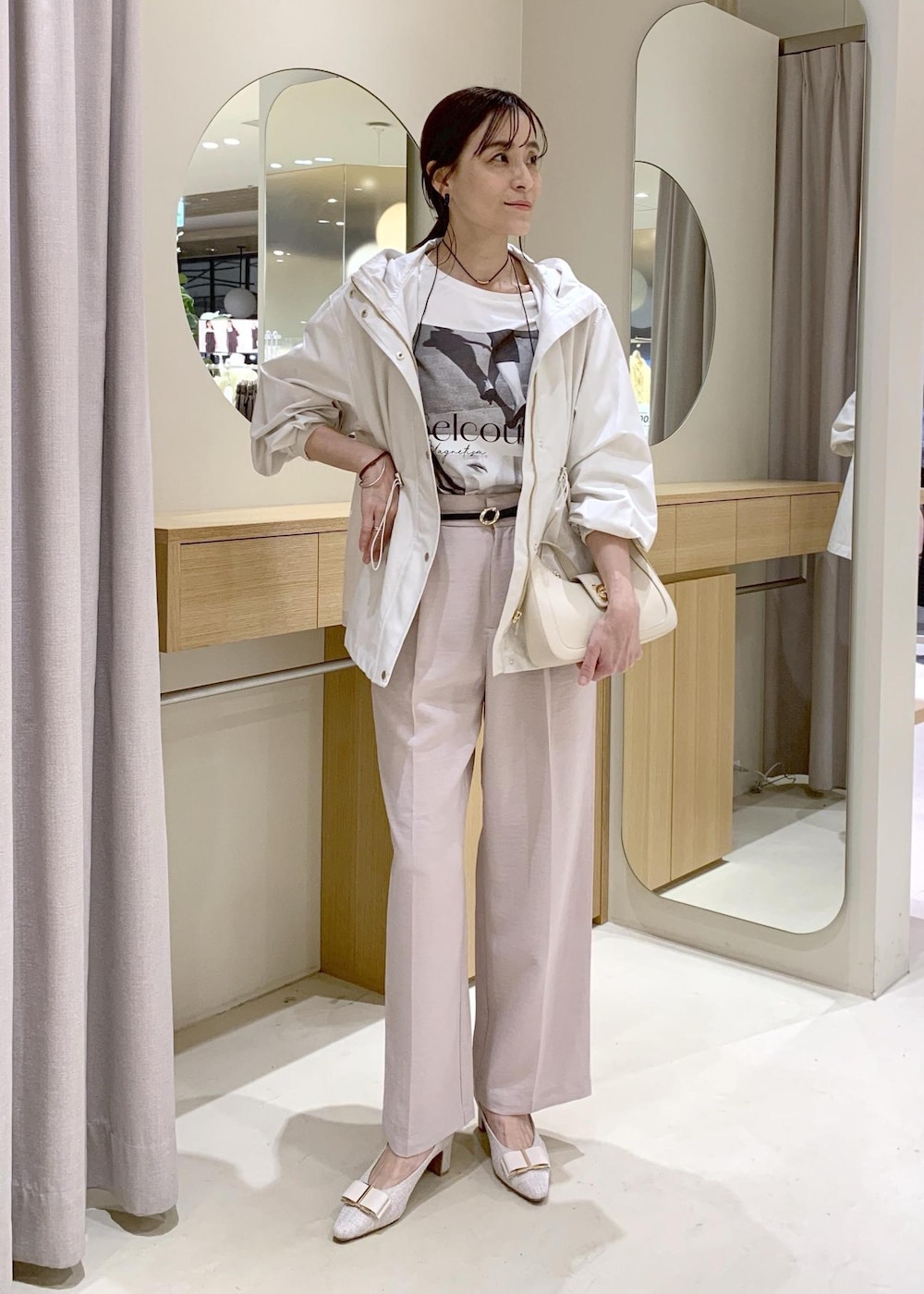 ホワイト系のショルダーバッグ、ベージュ系のパンプス、ホワイト系のナイロンジャケットを着用したレディースの春コーディネートの2枚目の写真