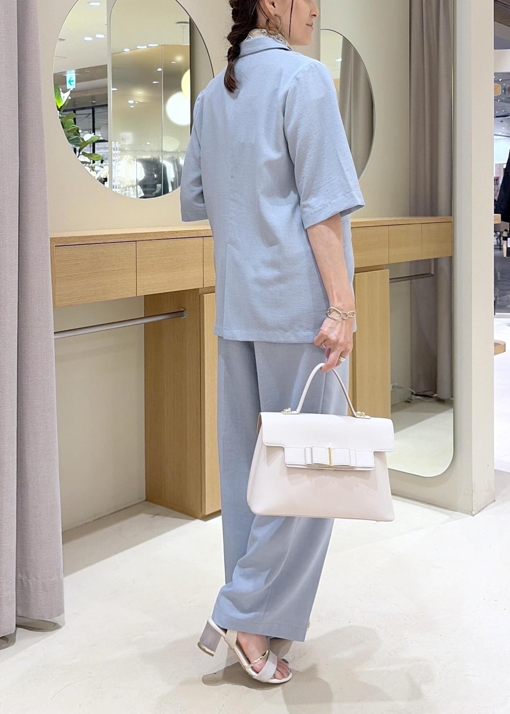 ホワイト系のハンドバッグ、ホワイト系のサンダル、ブルー系のその他パンツを着用したレディースの春コーディネートの4枚目の写真