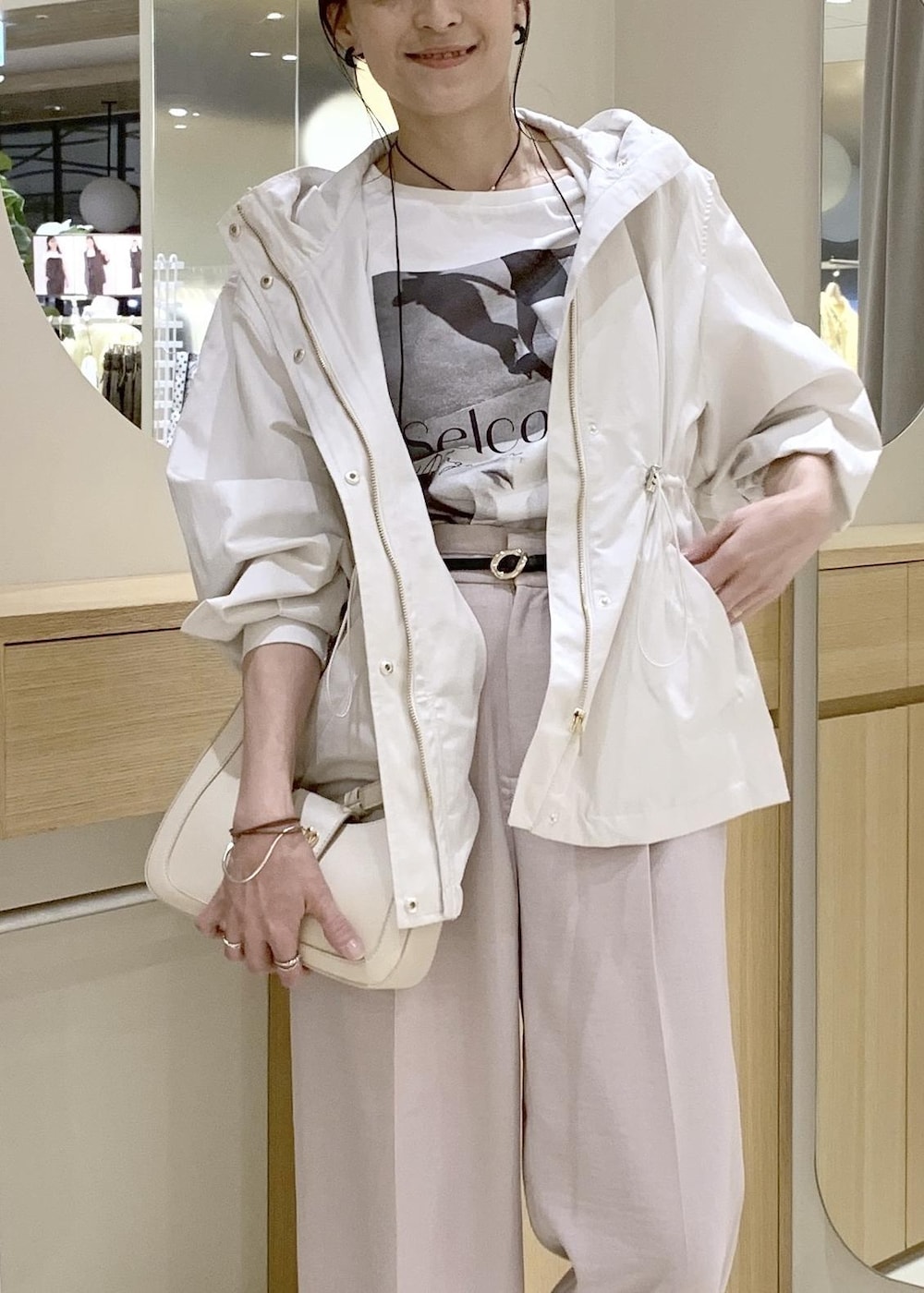 ホワイト系のショルダーバッグ、ベージュ系のパンプス、ホワイト系のナイロンジャケットを着用したレディースの春コーディネートの8枚目の写真