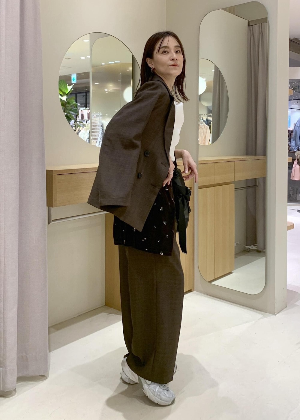 ブラック系のトートバッグ、ブラウン系のカーディガン/ボレロ、ホワイト系のニット/セーターを着用したレディースの春コーディネートの3枚目の写真