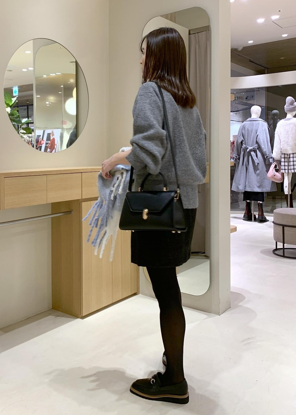 ブラック系のローファー、ブラック系のハンドバッグ、ブラック系のスカートを着用したレディースの冬コーディネートの3枚目の写真