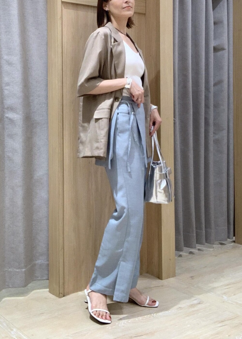 ホワイト系のキャミソール、ホワイト系のサンダル、ブルー系のスラックスを着用したレディースの夏コーディネートの4枚目の写真