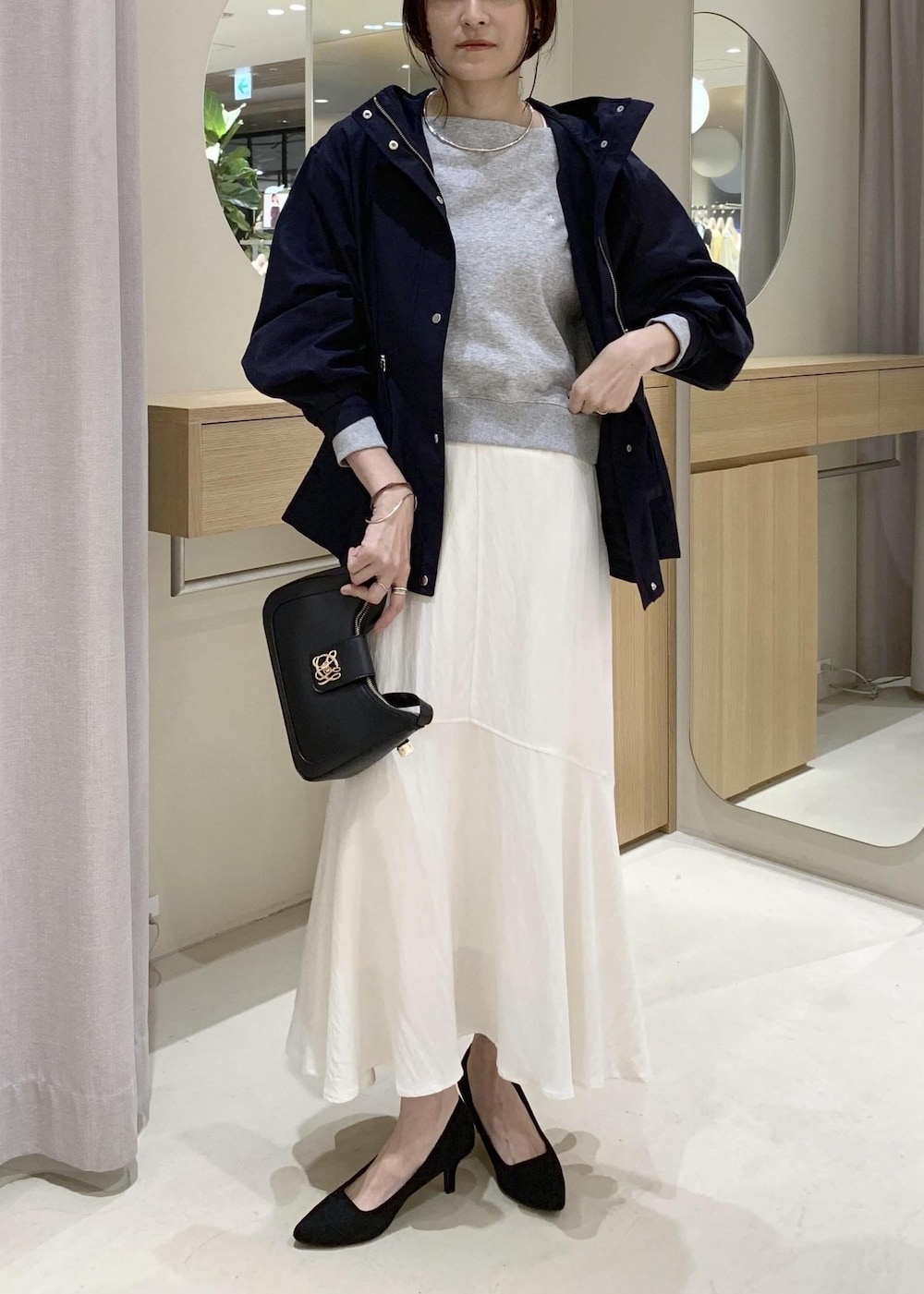 ブラック系のショルダーバッグ、ブルー系のナイロンジャケット、ホワイト系のキャミソールを着用したレディースの春コーディネートの2枚目の写真