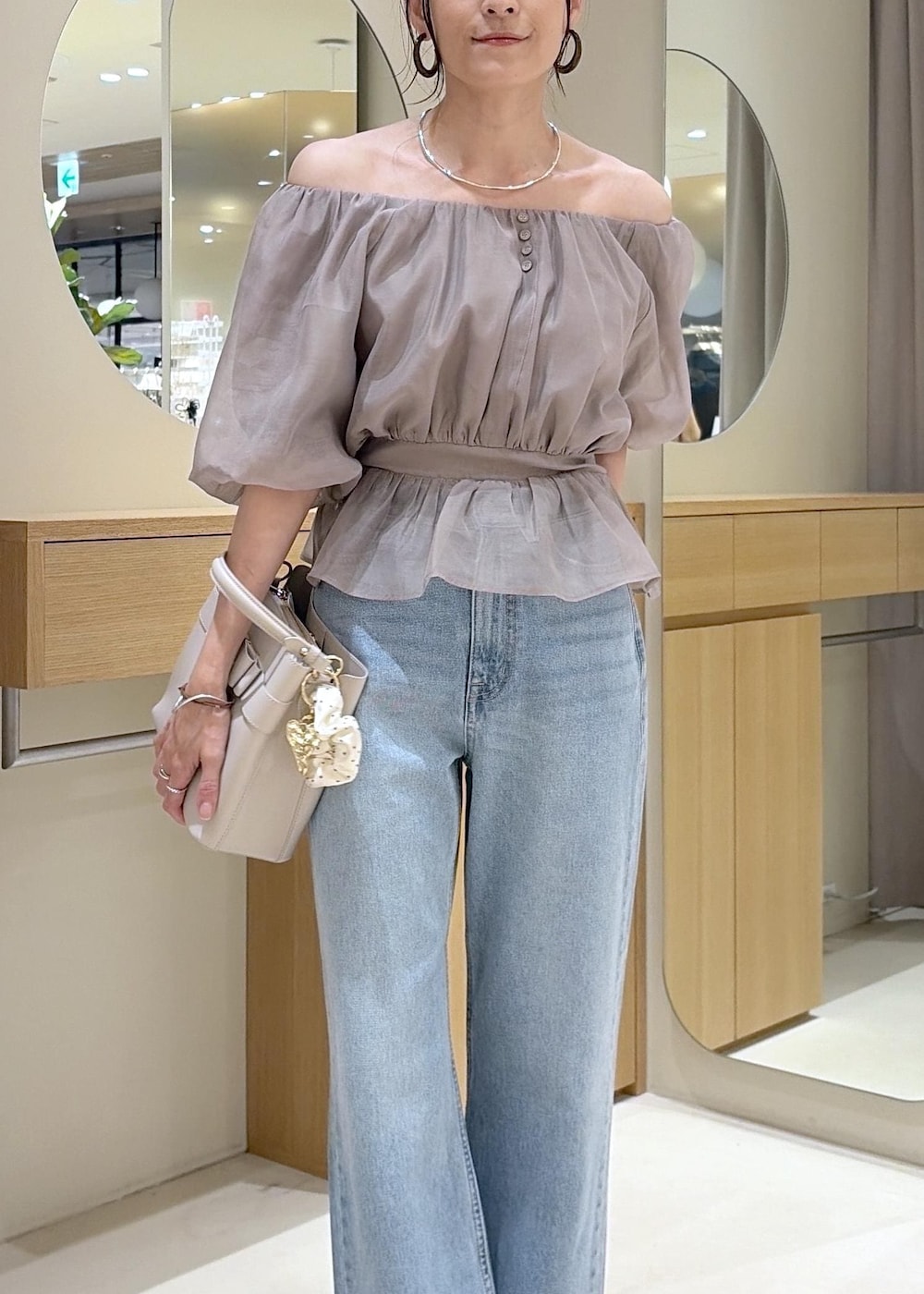 ホワイト系のパンプス、ベージュ系のシャツ/ブラウス、ブルー系のデニムパンツを着用したレディースの夏コーディネートの7枚目の写真