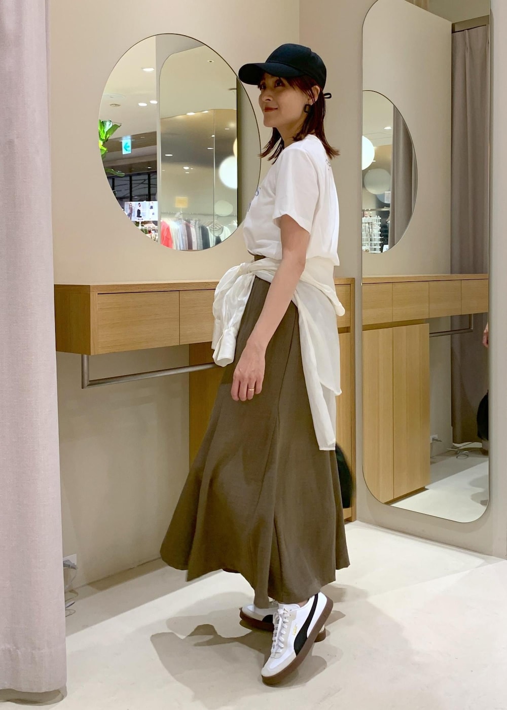 グリーン系のスカート、ホワイト系のシャツ/ブラウス、ブラック系のハンドバッグを着用したレディースの春コーディネートの2枚目の写真