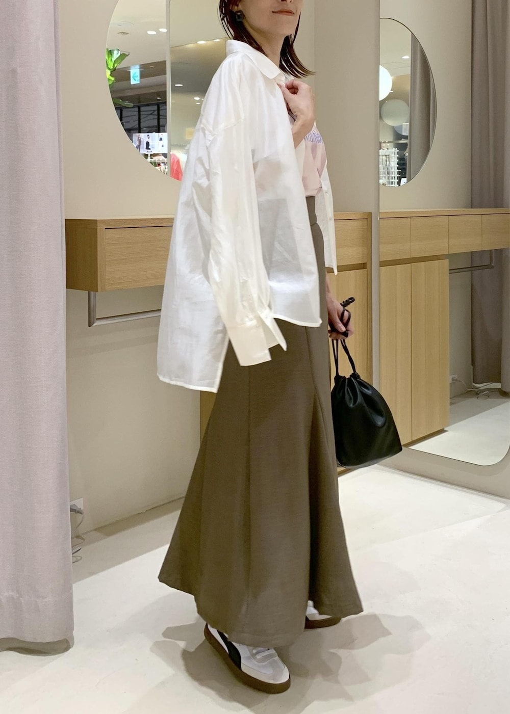 グリーン系のスカート、ホワイト系のシャツ/ブラウス、ブラック系のハンドバッグを着用したレディースの春コーディネートの4枚目の写真