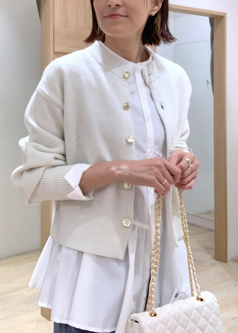 ホワイト系のショルダーバッグ、ホワイト系のカーディガン/ボレロ、ホワイト系のブーツを着用したレディースの秋コーディネートの5枚目の写真