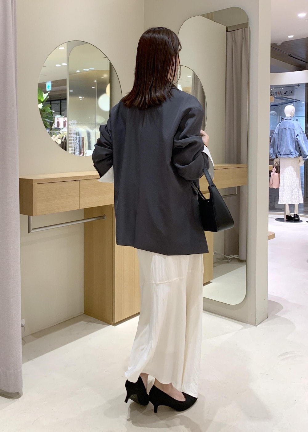 ブラック系のショルダーバッグ、ホワイト系のシャツ/ブラウス、ホワイト系のスカートを着用したレディースの春コーディネートの5枚目の写真