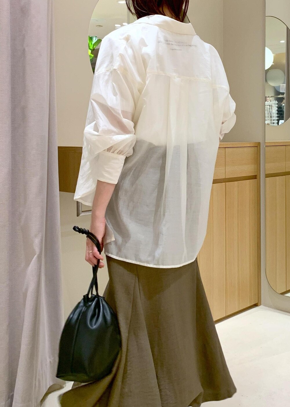 グリーン系のスカート、ホワイト系のシャツ/ブラウス、ブラック系のハンドバッグを着用したレディースの春コーディネートの8枚目の写真