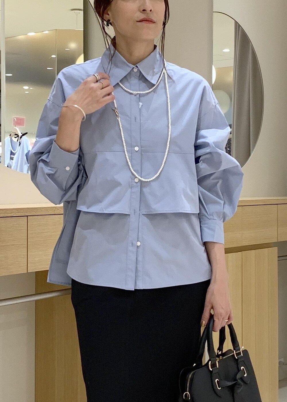 ブラック系のパンプス、ブラック系のスカート、ブルー系のシャツ/ブラウスを着用したレディースの夏コーディネートの6枚目の写真