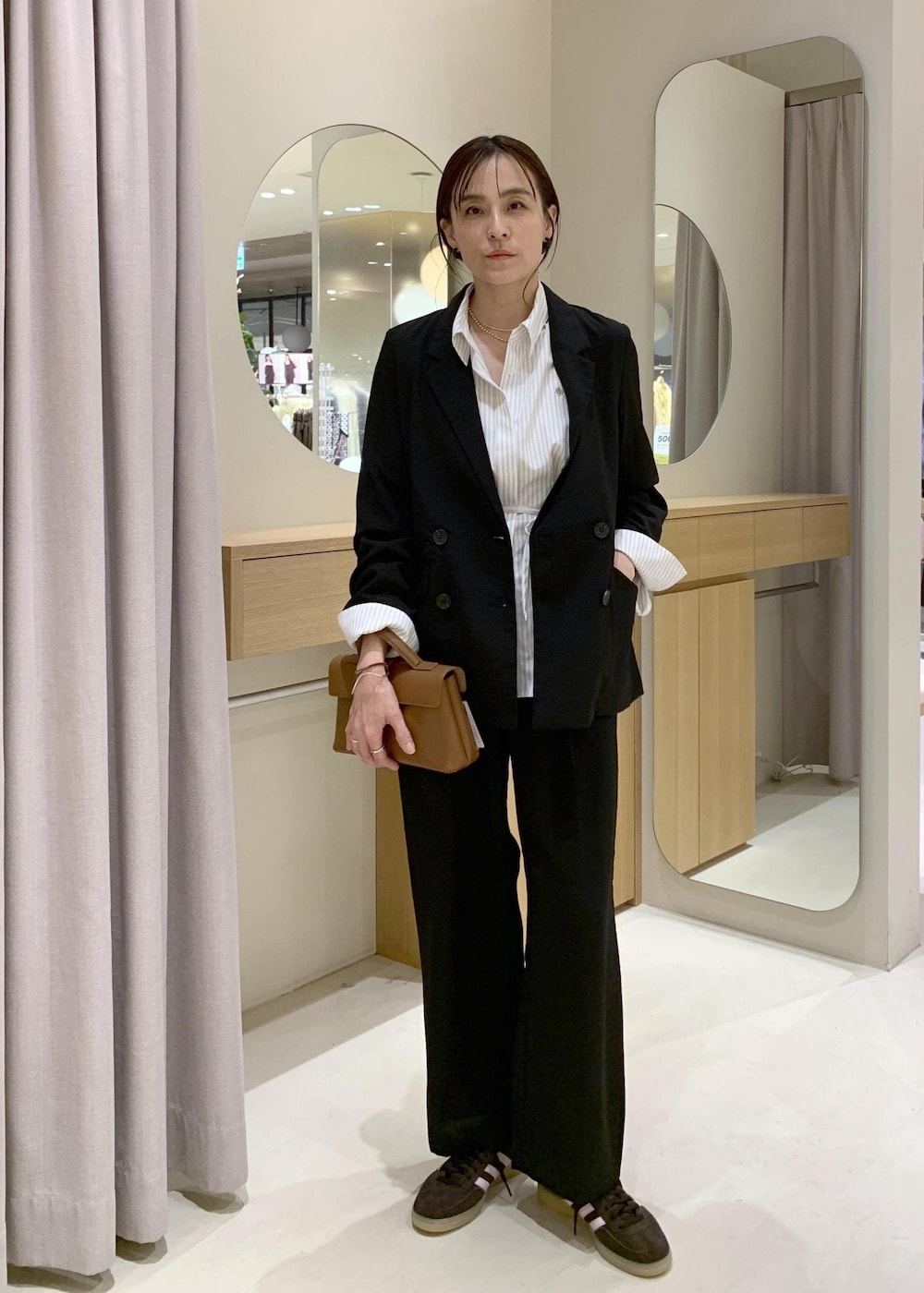 イエロー系のショルダーバッグ、ブラック系のテーラードジャケット、ブラック系のその他パンツを着用したレディースの春コーディネートの2枚目の写真