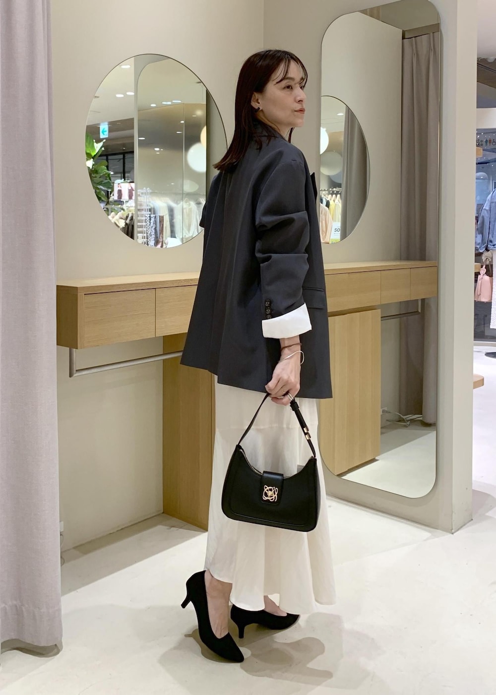 ブラック系のショルダーバッグ、ホワイト系のシャツ/ブラウス、ホワイト系のスカートを着用したレディースの春コーディネートの3枚目の写真