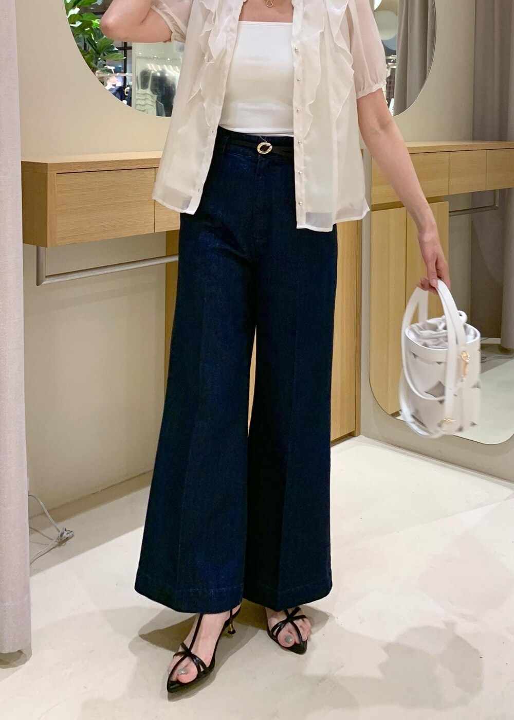 ホワイト系のキャミソール、ブラック系のサンダル、ブルー系のデニムパンツを着用したレディースの夏コーディネートの9枚目の写真