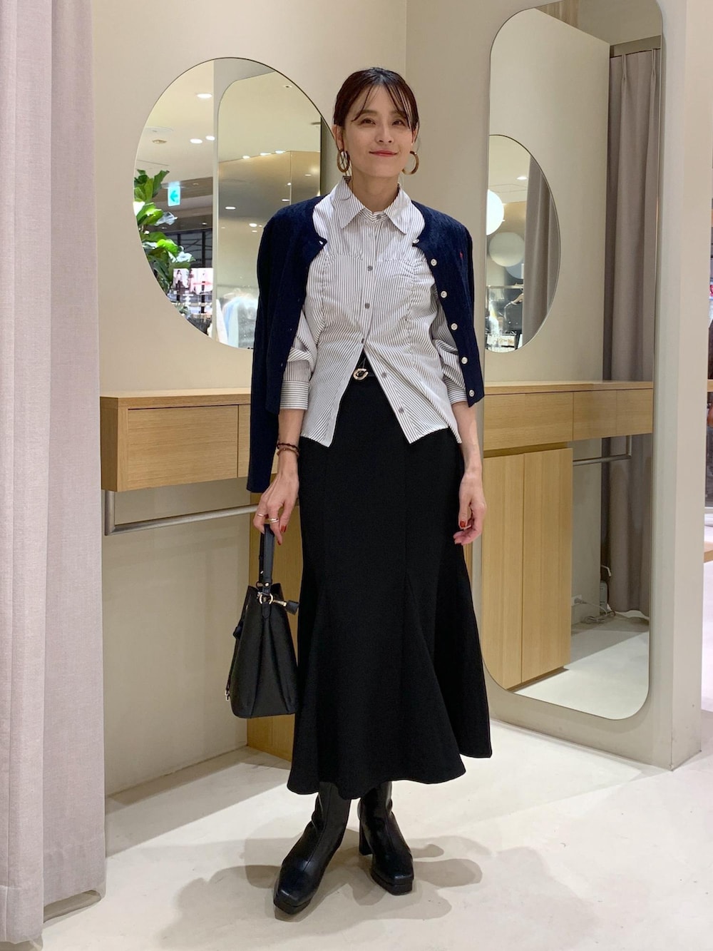 ブラック系のショルダーバッグ、ブラック系のスカート、ブルー系のカーディガン/ボレロを着用したレディースの秋コーディネートの2枚目の写真